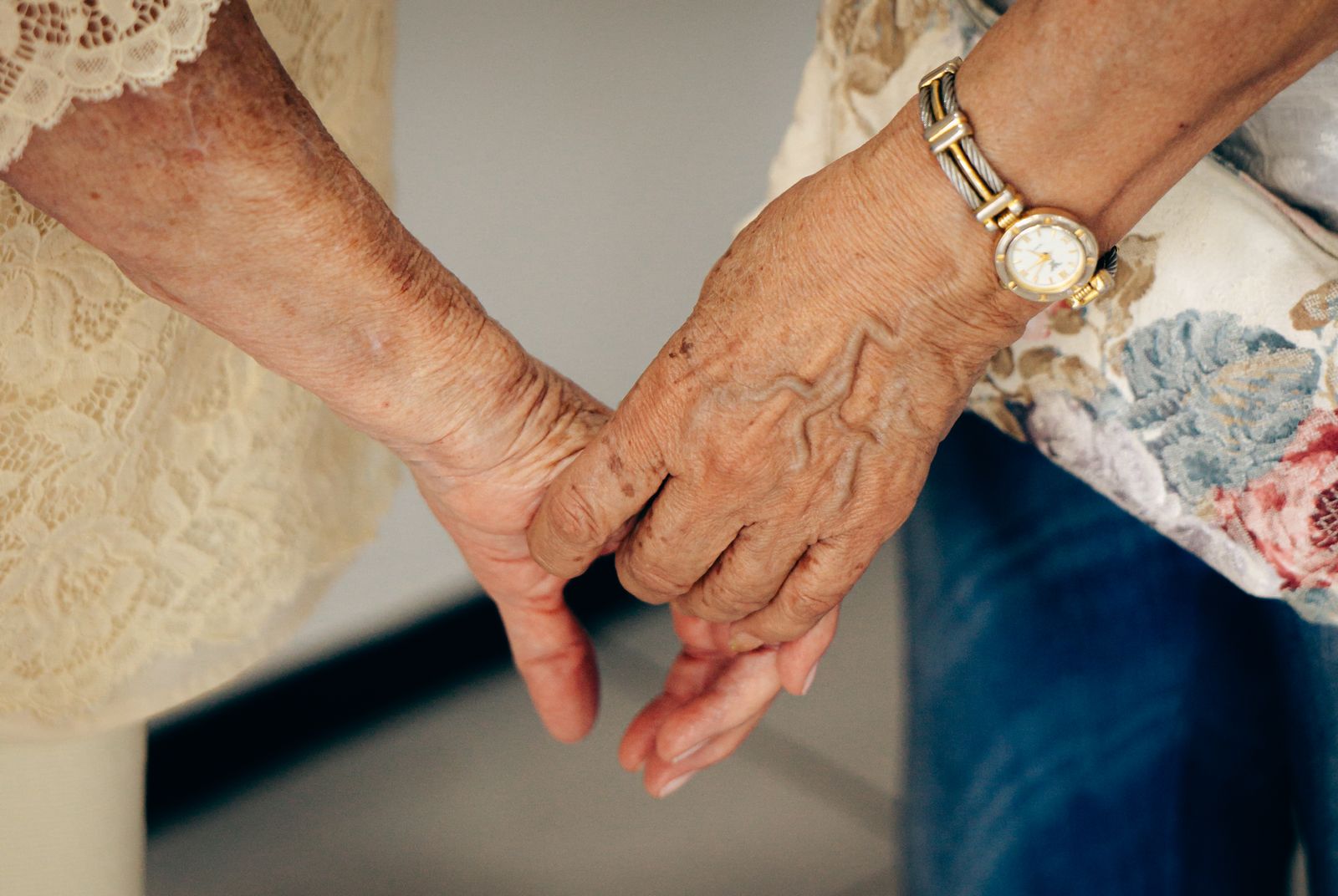 Close-up of an elderly woman's hands held gently by a caregiver, symbolizing trust and companionship