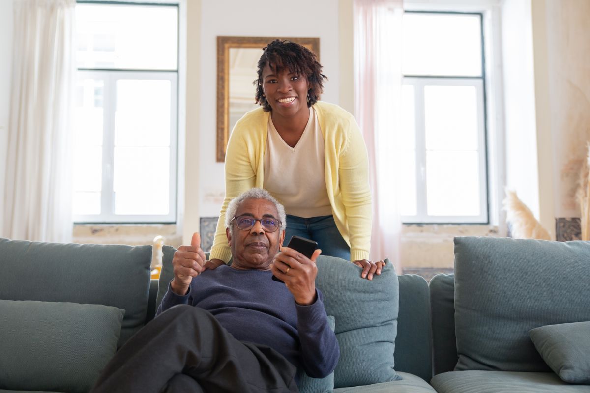 A smiling caregiver and senior client sharing a joyful moment together at home
