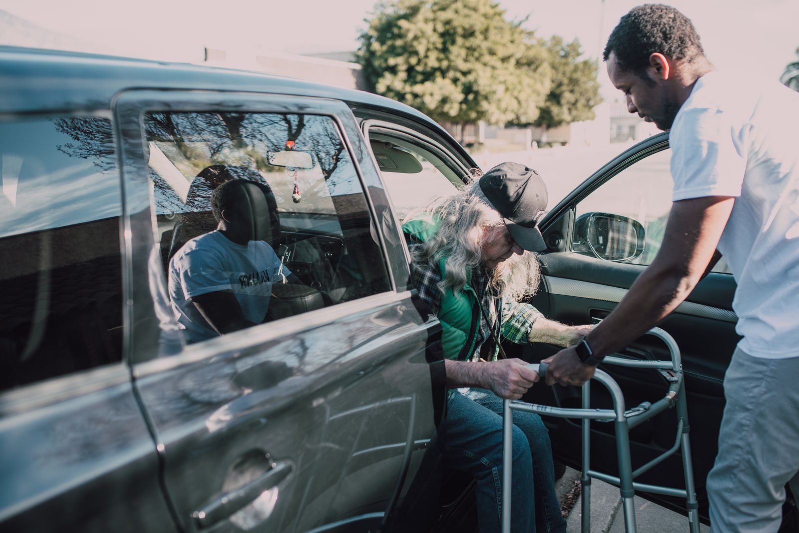 A caregiver helping a senior client into a car for a ride to an appointment